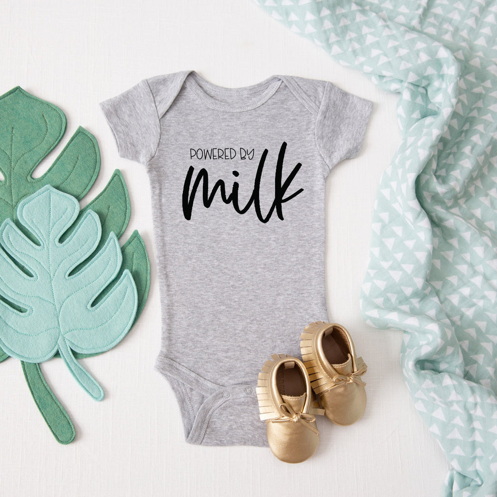 Powered by Milk baby bodysuit lifestyle photo - gray bodysuit laid flat on a leaf-print background