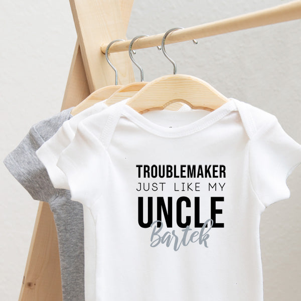 Troublemaker, Just Like My Uncle personalized baby bodysuit lifestyle photo - white bodysuit hanging on a wooden hanger, close-up
