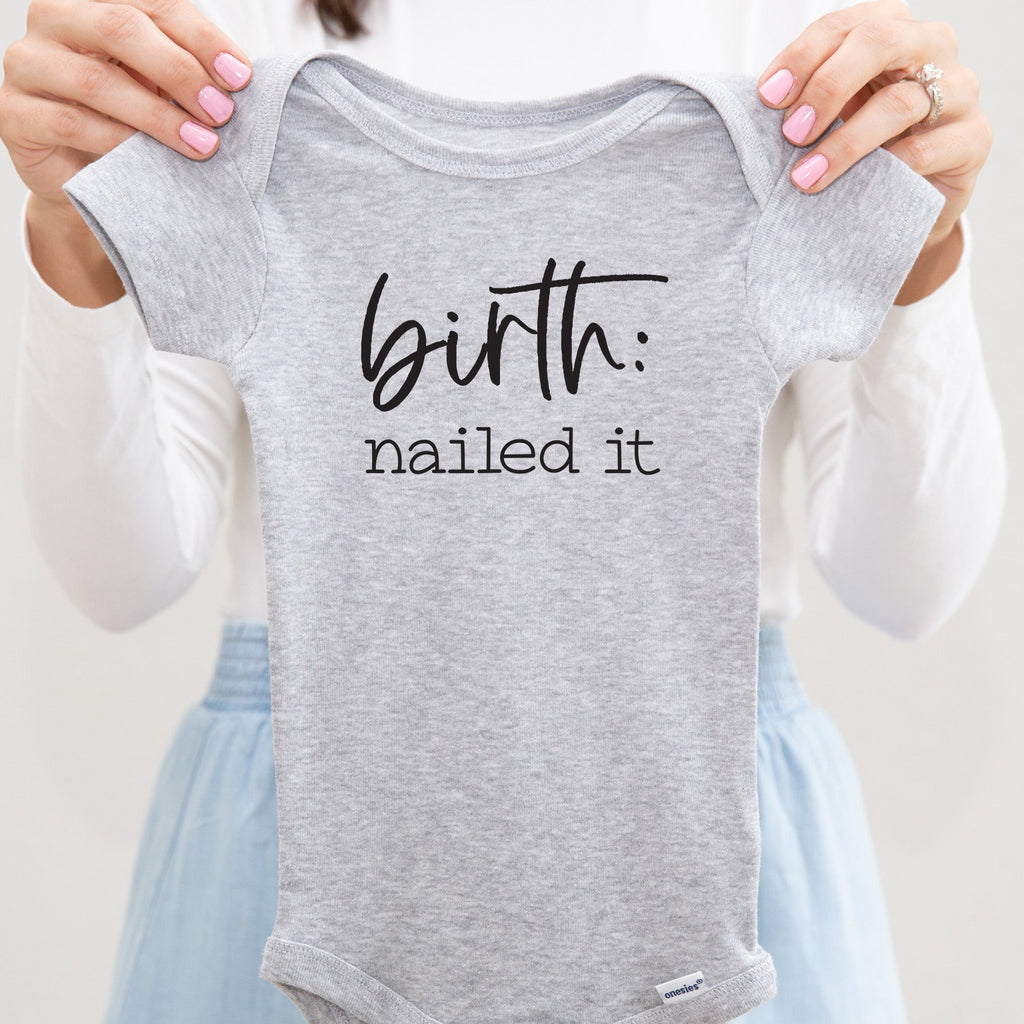 Birth: Nailed It baby bodysuit lifestyle photo - gray bodysuit being held by an adult