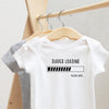 Diaper Loading, Please Wait.... baby bodysuit lifestyle photo - white bodysuit hanging on a wooden hanger, close-up