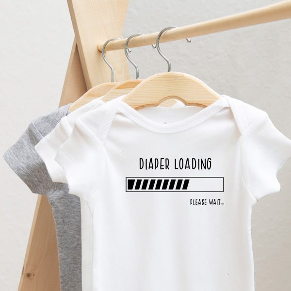 Diaper Loading, Please Wait.... baby bodysuit lifestyle photo - white bodysuit hanging on a wooden hanger, close-up