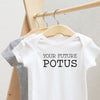 Your Future POTUS baby bodysuit lifestyle photo - white bodysuit hanging on a wooden hanger, close-up