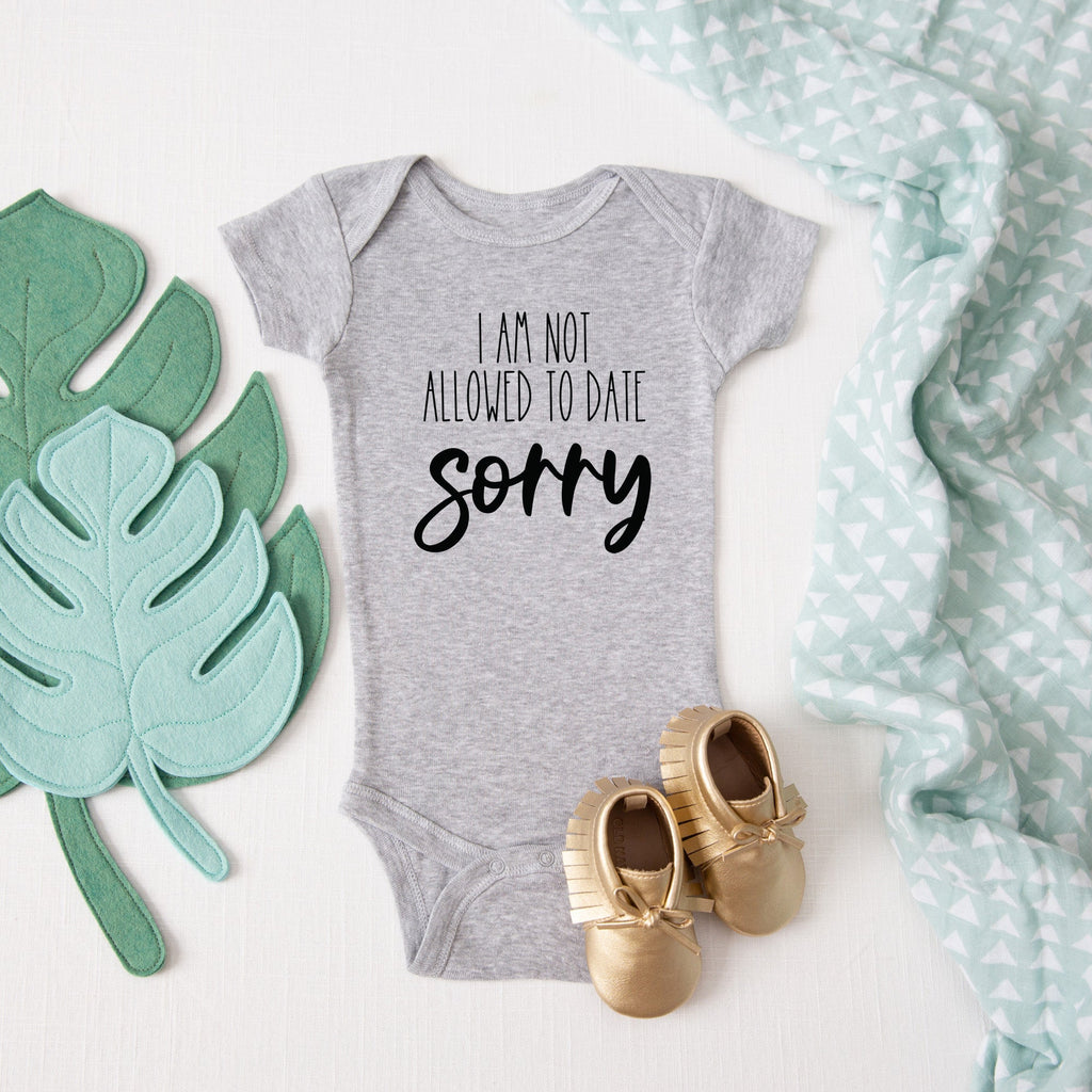 I'm Not Allowed to Date, Sorry baby bodysuit lifestyle photo - gray bodysuit laid flat on a leaf-print background