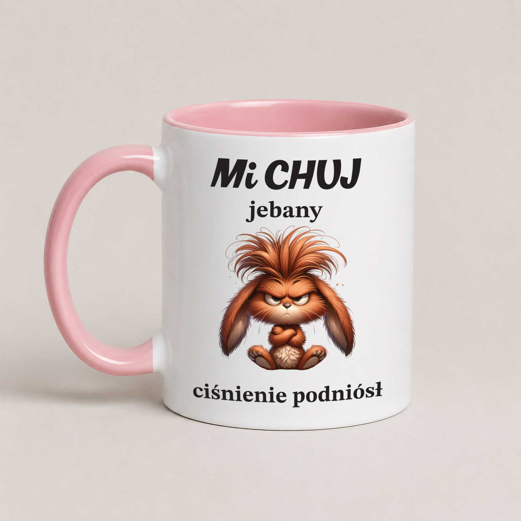 A white ceramic mug with a pink handle and interior, featuring a cartoon illustration of an angry orange-brown creature and Polish text on the front, set against a plain light beige background.