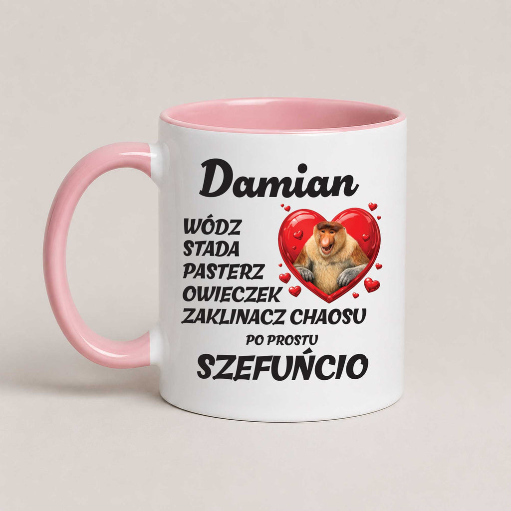 A white ceramic coffee mug with a pink handle and interior, featuring Polish text and a cartoon chameleon inside a red heart on a light beige background.