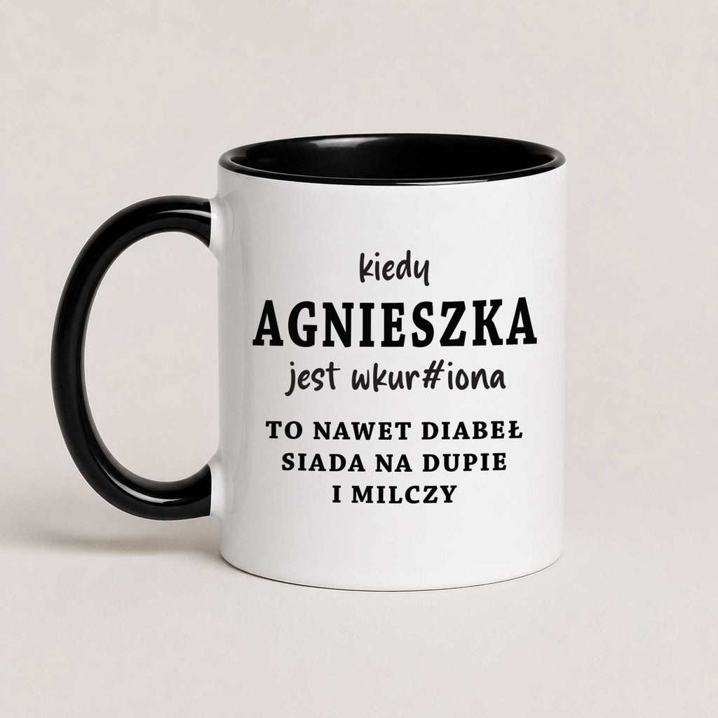 A Black 11oz ceramic mug with the personalized Polish quote 'Kiedy Agnieszka jest wkur#iona, to nawet diabeł siada na dupie i milczy', customizable with any name