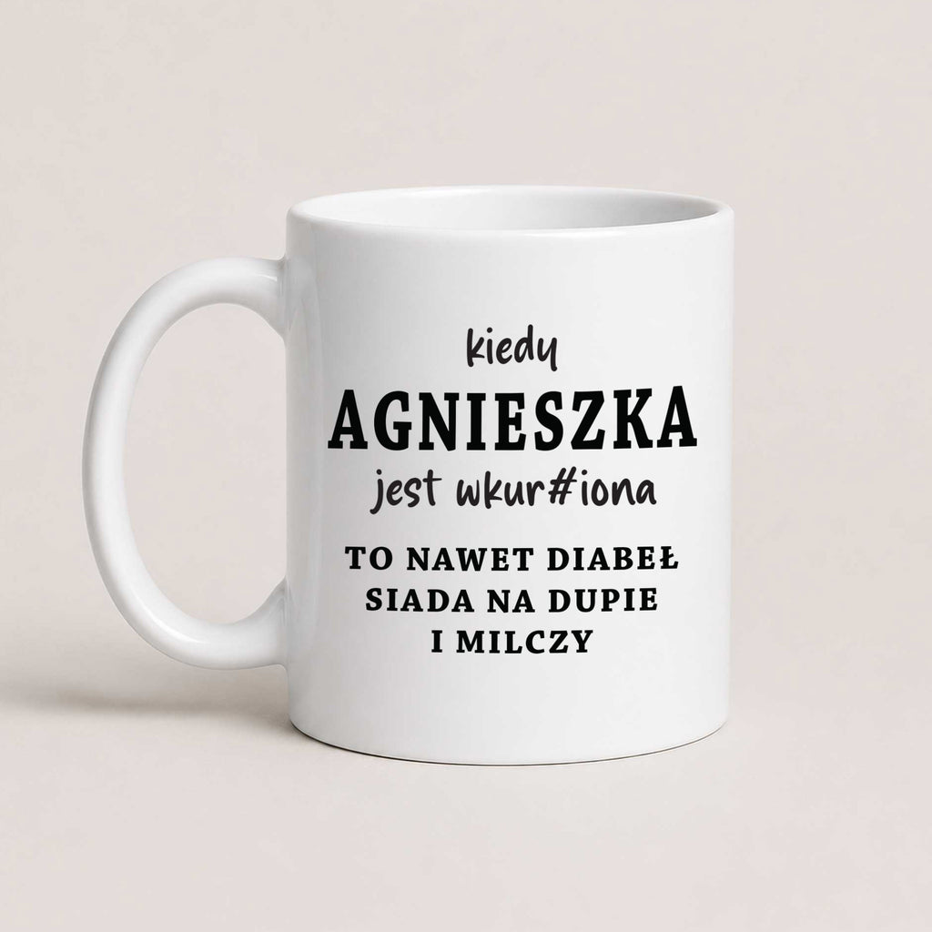 A White 11oz ceramic mug with the personalized Polish quote 'Kiedy Agnieszka jest wkur#iona, to nawet diabeł siada na dupie i milczy', customizable with any name
