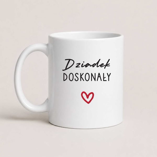 A White 11oz ceramic Polish coffee mug featuring the 'Dziadek Doskonały' design with a subtle heart accent